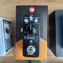 Černý kytarový pedál s nápisy MID, BASS, TREBLE, COMP, GATE a REVERB. Uprostřed je velký černý otočný ovladač s nápisem VOL / GAIN a pod ním výrazný…