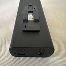 Černý obdélníkový modul s matným povrchem. Na horní části je plastový držák, pod kterým je viditelný bílý štítek s nápisy "Power supply", "DC 5V" a "…