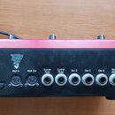 Zátylový panel černého elektronického zařízení s červeným horním okrajem. Jsou zde vidět konektory a nápisy: PCMCIA slot, Midi In, Midi Out, Sustain…