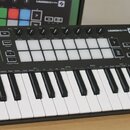 Černý kompaktní MIDI kontrolér s klávesnicí a mřížkou 16 bílých čtvercových padů. Na horním panelu je nápis LAUNCHKEY mini a řada ovládacích prvků s…
