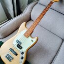 Zlatá elektrická basová kytara s bílým pickguardem a hnedým hmatníkem. Na hlavě je nápis Fender MUSTANG BASS. Tělo i krk vykazují hladký povrch bez v…