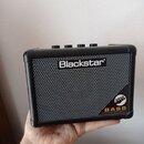 Černý kompaktní basový kombozesilovač s kovovou mřížkou reproduktoru. Na přední straně je bílý nápis Blackstar a v pravém dolním rohu žlutý nápis BAS…