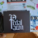 Fotografie zobrazuje černou krabici s bílým logem „Pedal pawn“. Vedle ní je manuál s nápisem „TEXAN TWANG“ a logem „Pedal pawn“, který obsahuje sezna…