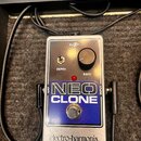Stříbrný efekt pedál s modrým panelem a nápisem NEO CLONE. V horní části jsou ovládací prvky Depth (přepínač) a Rate (otočný knoflík), nápis 9V oraz…