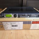 Černý rackový zvukový modul Yamaha Motif-Rack ES umístěný na originální kartónové krabici s nápisy YAMAHA CORPORATION a MOTIF. Na předním panelu je d…