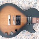 Elektrická kytara s tmelem v přechodu od černé k hnědé a žluté barvě. Na těle jsou dva černí humbuckery, stříbrný kobylník a strunový most. V dolní č…