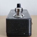 Černý efekt pedál s texturovaným povrchem a kovovým spínacím tlačítkem. Na přední hraně je nápis tc electronic. V horní části je vidět černý ovládací…