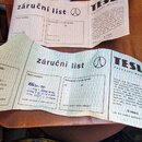Fotografie zachycuje papírový záruční list značky TESLA VALASSKE MEZIRICI. Dokument obsahuje text v češtině, razítka a ručně psané poznámky. V levém…