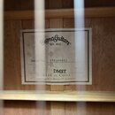 Detail štítku uvnitř akustické kytary. Na bílém štítku je nápis Sigma Guitars EST. 1970, Serial No. 170308463 a model DMST. Dole je uveden text MADE…