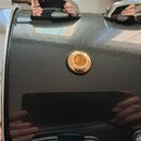 Detail korpusu černého bubnu s kovovými obručemi. Uprostřed je umístěno kulaté zlaté logo s nápisem SINCE 1946 PEARL a RUDY. Povrch nástroje je černý…
