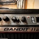 Detailní pohled na ovládací panel kytarového komba s nápisem BANDIT 112. Panel obsahuje ovládací knoflíky s popisky POST GAIN, REVERB, PRESENCE a MAS…
