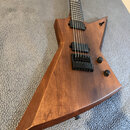 Elektrická kytara s hrotovitým tělem z hnědého dřeva s viditnou masivním strukturou. Nástroj má dva černé humbuckery, černý most s nápisem "TUNE-O-MA…