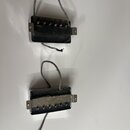 Dvě elektrické kytarové snímače typu humbucker v černé barvě s kovovými kryty. Na spodním snímači je na kovové části vyražen nápis PAT. NO. 2,575,842…