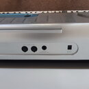 Detail zadní strany stříbrného elektronického klávesu. Jsou vidět tři konektory s nápisy OUT, PHONES a SUSTAIN / PROGRAMMABLE JACK a vstup pro napáje…
