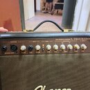 Hnědý akustický kytarový zesilovač s černým koženým potahem a zlatými kovovými detaily. Na horním ovládacím panelu je nápis 25W ACOUSTIC AMPLIFIER TR…