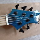 Hlava modré basové kytary s pěti strunami a černými ladičkami. Na povrchu je bílý nápis Marcus Miller M2 a logo Sire. Nástroj vykazuje známky používá…