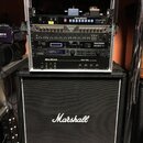 Stříbrný rack s osazenými zařízeními umístěný na černém kytarovém kombu značky Marshall. V racku jsou vidět přístroje s nápisy KORG, 48 tracks VM 100…