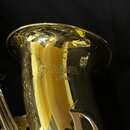 Detail zlatavého mosazného zvonu žemplovaného nápisy YAMAHA a JAPAN spolu s logem značky. Povrch je vysoce anodizovaný a zrcadlový, s viditelnými odl…