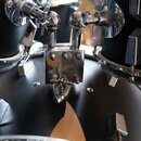 Detailní pohled na chromované držáky činelů připevněné k černým bubnům. Na středovém kovovém držáku je vyryt nápis SONOR a pod ním menší text MADE IN…
