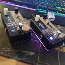 Dvě kytarové efekt pedály Octave Boost v černých kovových krabicích s ozdobným zlatým vzorem. Na obou je nápis OCTAVE BOOST, logo šipky směřující nah…