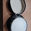 Bílý buben s kovovým obručem umístěný v otevřeném černém pouzdře s bílou vnitřní výstelou. Na blaně je modré logo a nápis BLUE LARGE. Povrch nástroje…