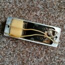 Fotografie znázorňuje vnitřek kovového šasi elektronického komponentu, pravděpodobně snímače. Uvnitř je vidět žlutá houbovitá vložka, černé plastové…