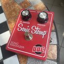 Červený efekt pedál s bílým nápisem Sonic Stomp a označením SONIC MAXIMIZER. Na horní straně jsou dva černé ovládací knoflíky s kovovými vršky a popi…