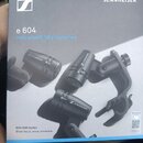 Fotografie znázorňuje krabici od mikrofonů s nápisy e 604 a Instrument Microphones. Na obalu jsou zobrazeny tři černé mikrofony s logem SENNHEISER a…