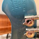 Detail zadní strany modré hlavy kytary s kovovými ladicími mechanismy značky GROVER. Na povrchu je vyražen nápis MADE IN USA 2017 MODEL a sériové čís…