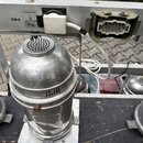Detailní pohled na kovové stříbrné osvětlovací reflektory umístěné na černém povrchu. Na horní liště jsou vidět nápisy CH-2, Fixation point a 5kg s i…
