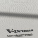 Fotografie znázorňuje bílý mesh obal na elektronický buben. V horní části je nápis „Roland“, pod ním text „MESH HEAD“ a „Reg. U.S. Pat. & Tm. Off.“.…