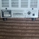 Zadní strana bílého kytarového zesilovače s kovovou rukojetí. Na štítku je uvedeno logo ORANGE, MODEL MICRO TERRIER, TYPE AMPLIFIER HEAD a POWER 25 W…