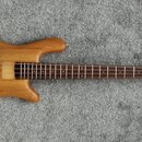Elektrická basová kytara s přírodním dřevěným povrchem těla a hmatníkem z tmavého dřeva. Na hlavě je viditelný nápis "Squier". Nástroj má dva snímače…
