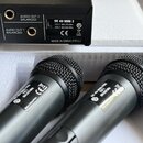 Dva bezdrátové mikrofony s černými mřížkami a stříbrno-šedým tělem. Na štítcích mikrofonů je uveden model HT 40 MINI PACK a frekvence ISM 2 864.375 M…