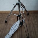 Chromovaný bubenový pedál s bílým šlapadlem. Na šlapadle je černý nápis Premier a grafické prvky ve tvaru blesků. Konstrukce vykazuje známky používán…