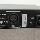 Detail zadní strany černého elektronického zařízení z kovu. Jsou vidět dva konektory XLR, nápisy CHANNEL ONE, XOVER FREQ., LOW OUT, LOW/HIGH, LOW/MID…
