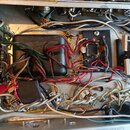 Fotografie zachycuje vnitřní zapojení elektronického zařízení s množstvím barevných vodičů a kabelů. Uprostřed je umístěn černý obdélníkový komponent…