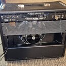 Zadní strana černého kytarového komba s nápisem MESA/BOOGIE. Horní panel obsahuje ovládací prvky, konektory a značku MESA. Spodní část je částečně ot…