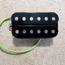 Černý humbucker s dvěma řadami šesti stříbrných pólů. K snímači vede zelený izolovaný kabel. Povrch je hladký a černý, bez viditelných značek, log ne…