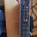 Zadní strana šedého audio rozhraní s různými konektory. Na zařízení je viditelné logo M-Audio a nápis Fast Track. Jsou zde popisky portů jako Front S…