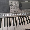 Šedý digitální klavír značky YAMAHA, model PSR-S770. Nástroj má v horní části ovládací panel s displejem, množstvím tlačítek a potenciometrů, vlevo j…