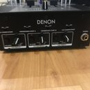 Černý DJ mixér značky DENON. Na předním panelu jsou nápisy CROSSFADER START A, CROSSFADER START B, CH2 FADER START a PHONES, dále ovládací prvky ozna…