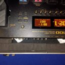 Detailní pohled na horní panel efektového procesoru GT-100 COSM AMP EFFECTS PROCESSOR. Zařízení má černý povrch a digitální displej, na kterém svítí…