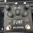 Černý kytarový efekt pedál s nápisy FLINT, tremolo & reverb a značkou strymon. Na horní části jsou tři černé ovládací knoflíky s popisky SPEED, DECAY…