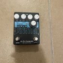 Černý efekt pedál s bílými ovládacími knoflíky. Na zařízení jsou nápisy bass MONO SYNTH, electro-harmonix a NEW YORK CITY, USA. Ovládací prvky jsou o…