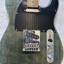 Elektrická kytara s modrozeleným průsvitným lakem, pod kterým je vidět výrazná struktura dřeva. Nástroj má černý pickguard a chromované části, včetně…
