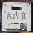 Bílá čtvercová krabice s nápisy a grafickými prvky. Uprostřed je velký černý nápis K.O.II a pod ním texty サンプラー a 128 MB SAMPLER COMPOSER. V horní čá…