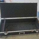 Otevřený transportní kufr s černým povrchem a hliníkovými hranami. Vnitřek víka je vyplněn černou akustickou pěnou s pyramidovým profilem, spodní čás…