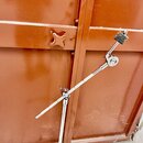 Stříbrný kovový mikrofonní stojan s výsuvným ramenem. Na konci ramene je umístěn černý plastový držák na mikrofon. Povrch stojanu vykazuje drobné zná…