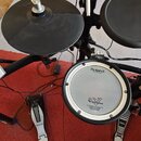 Elektronická bicí souprava značky Roland s modulem TD-9. Sestava obsahuje černý rám, dva gumové pady, jeden černý činel a bílý snare s nápisem Roland…